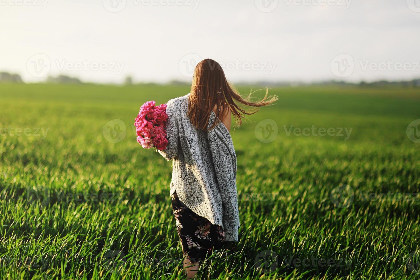mooi jong vrouw Aan een wandelen, de meisje in bloemen. boeket van pioen. elegant jong vrouw met prachtig haar. een meisje met pioen wandelingen in de veld. foto