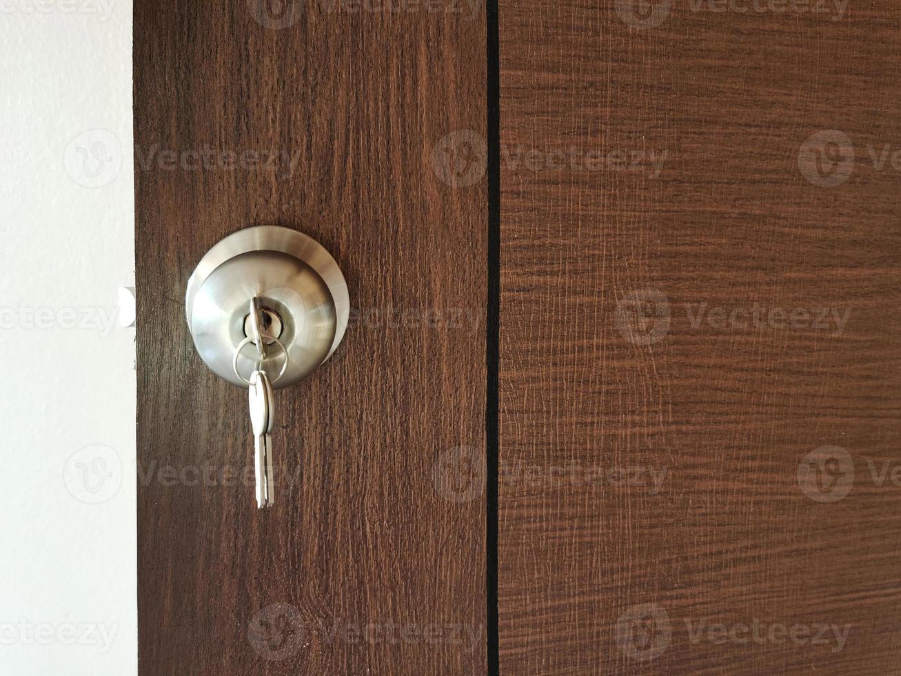 huis sleutel met huis sleutelhanger in sleutelgat Aan hout deur foto