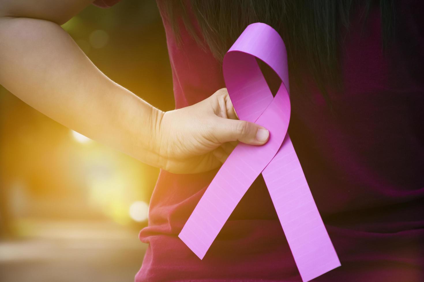 roze papier lint Holding in handen van vrouw tiener naar tonen en naar telefoontje uit allemaal mensen in de omgeving van de wereld naar ondersteuning en naar bijwonen de borst kanker campagne van vrouw, zacht en selectief focus. foto