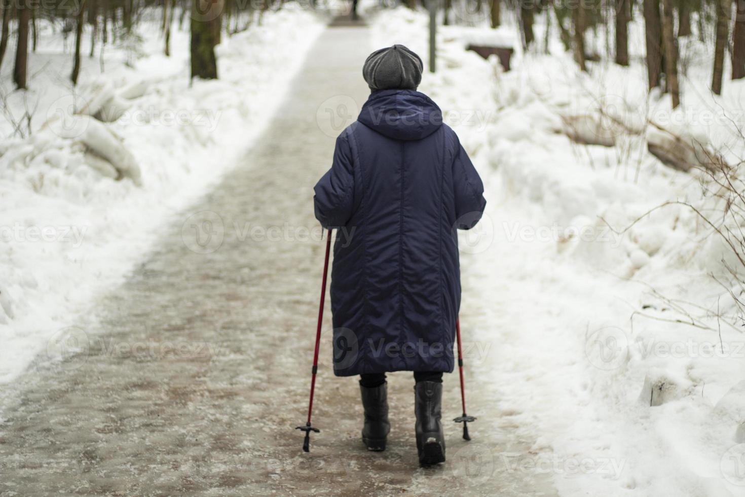 oma met wandelen polen in winter. gepensioneerd vrouw. gepensioneerde wandelingen door park. foto