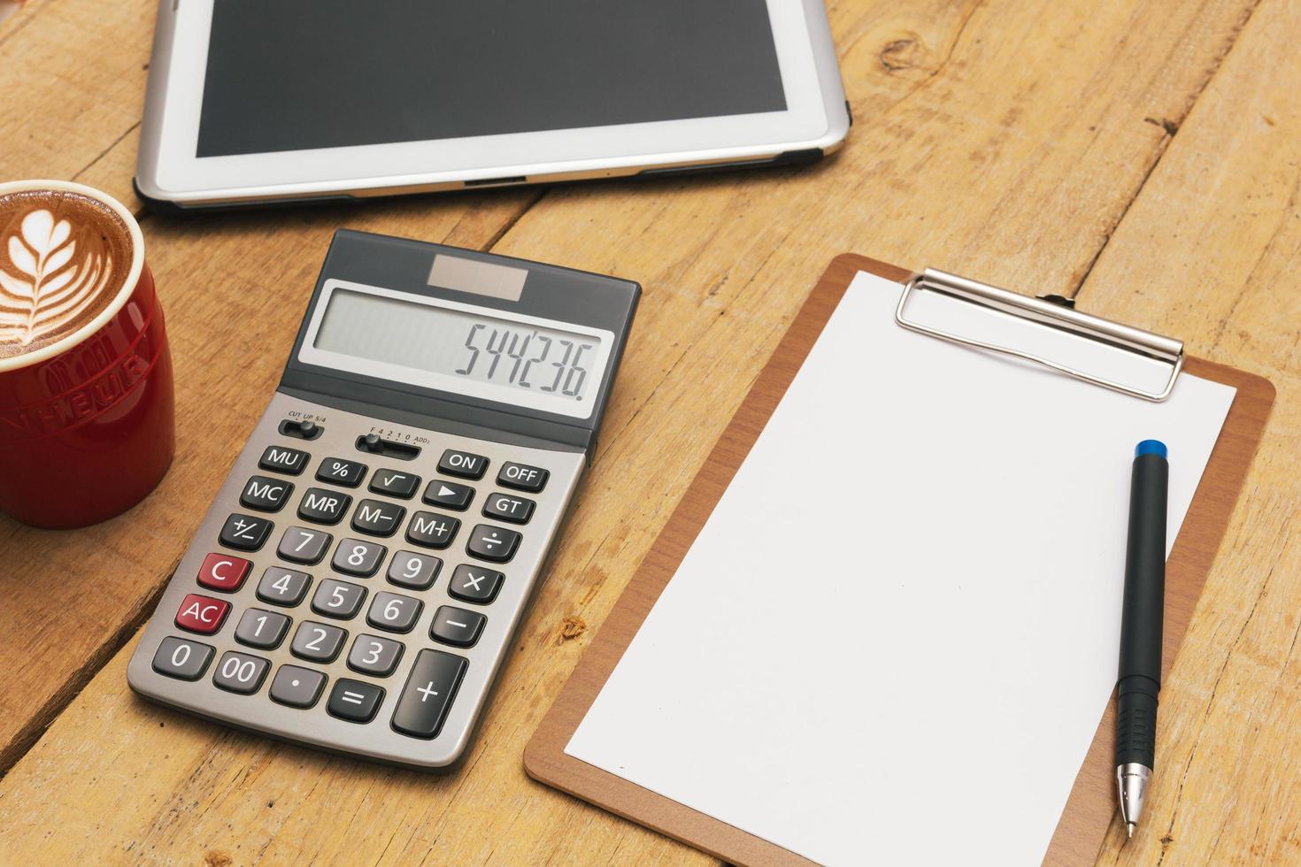 het bovenaanzicht van het bureau blanco papier, pen, rekenmachine, tablet. financiële planning en werkconcept. foto