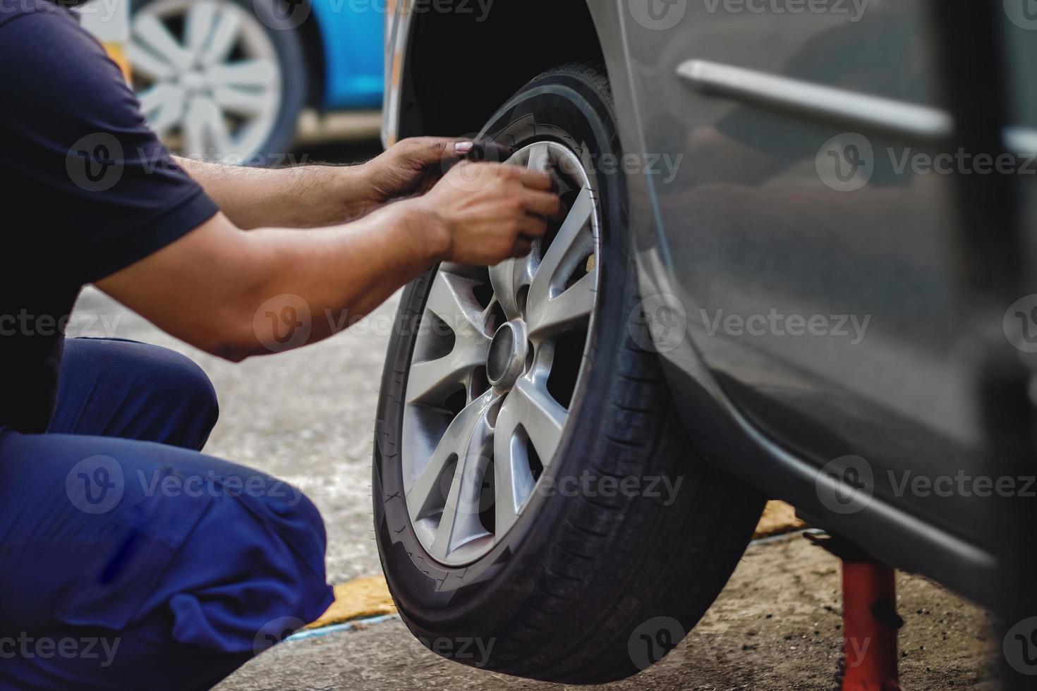 band vervanging concept. monteur werken zijn baan met wiel in garage. auto onderhoud en Diensten foto