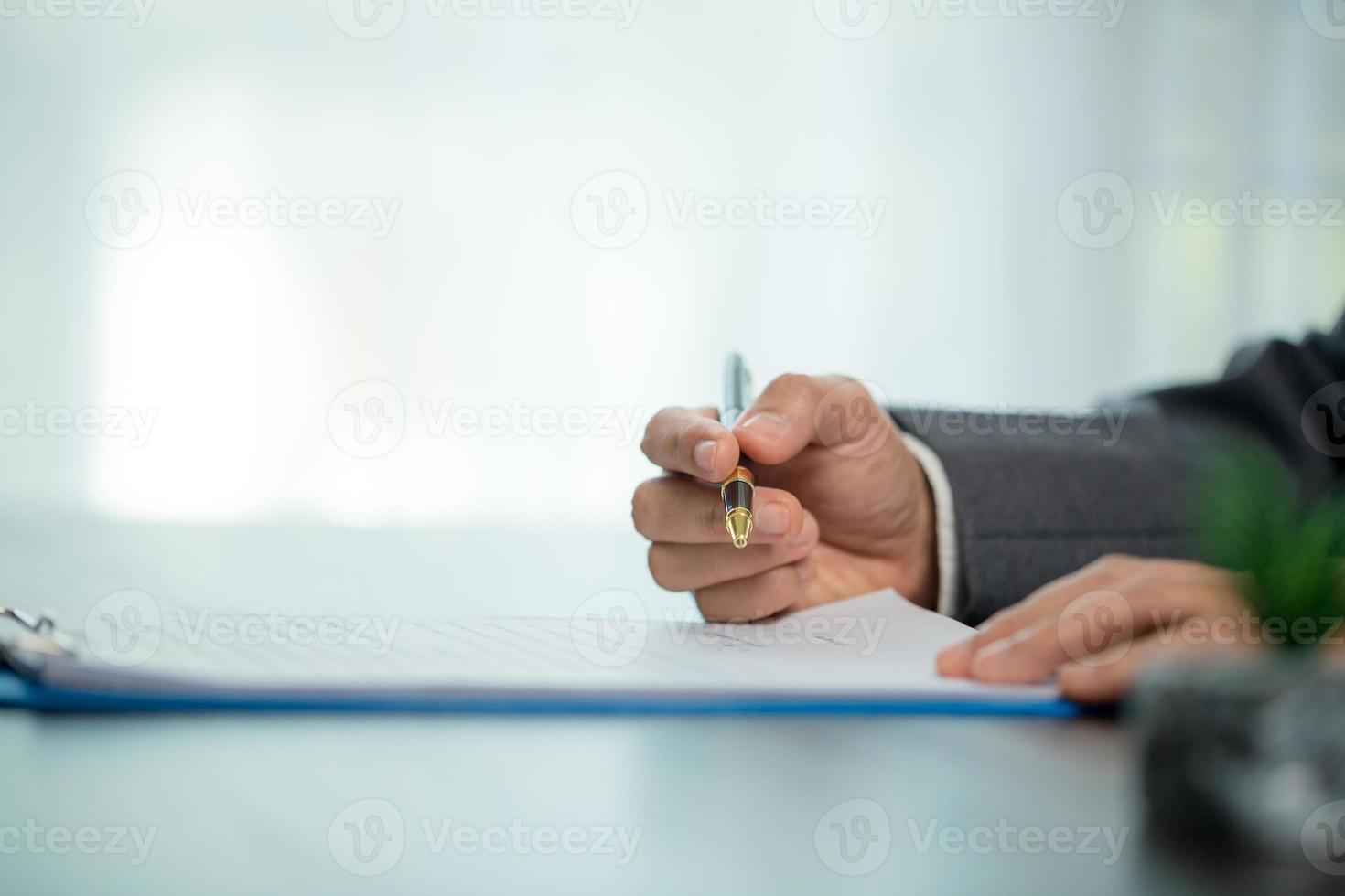 werkplaats detailopname persoon professioneel zakenvrouw zittend Bij bureau houden pen ondertekening of handtekening contract papier. werknemer vrouw schrijven overeenkomst document Aan papierwerk het formulier zakelijke Bij werk kantoor foto