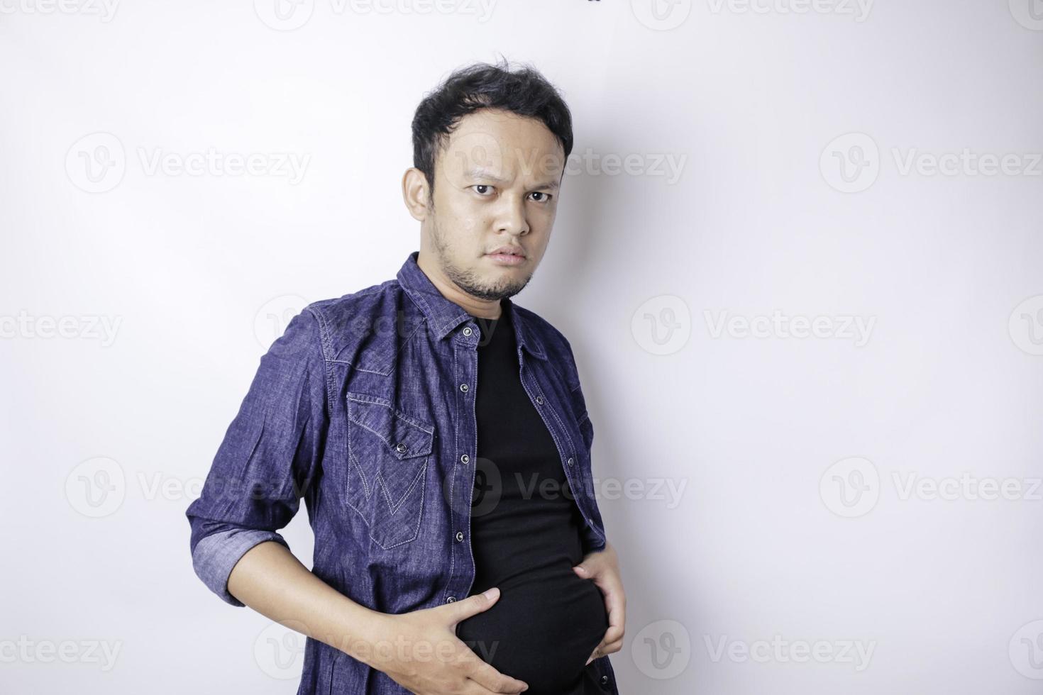een portret van onzeker Aziatisch dik Mens is Holding de dik in de omgeving van zijn taille foto