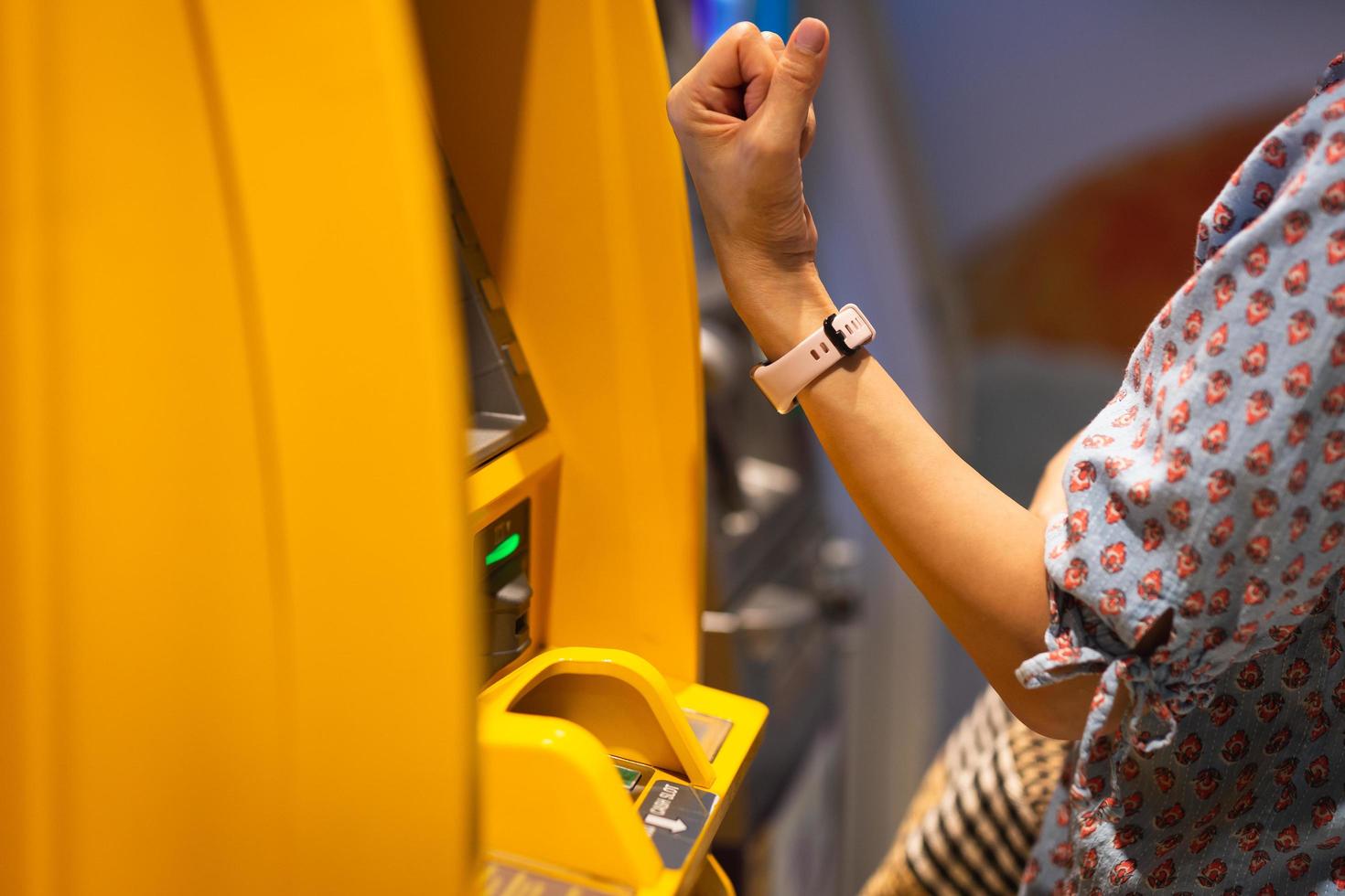 vrouw gebruik makend van draadloze systeem Aan slim kijk maar Bij Geldautomaat contant geld machine. foto