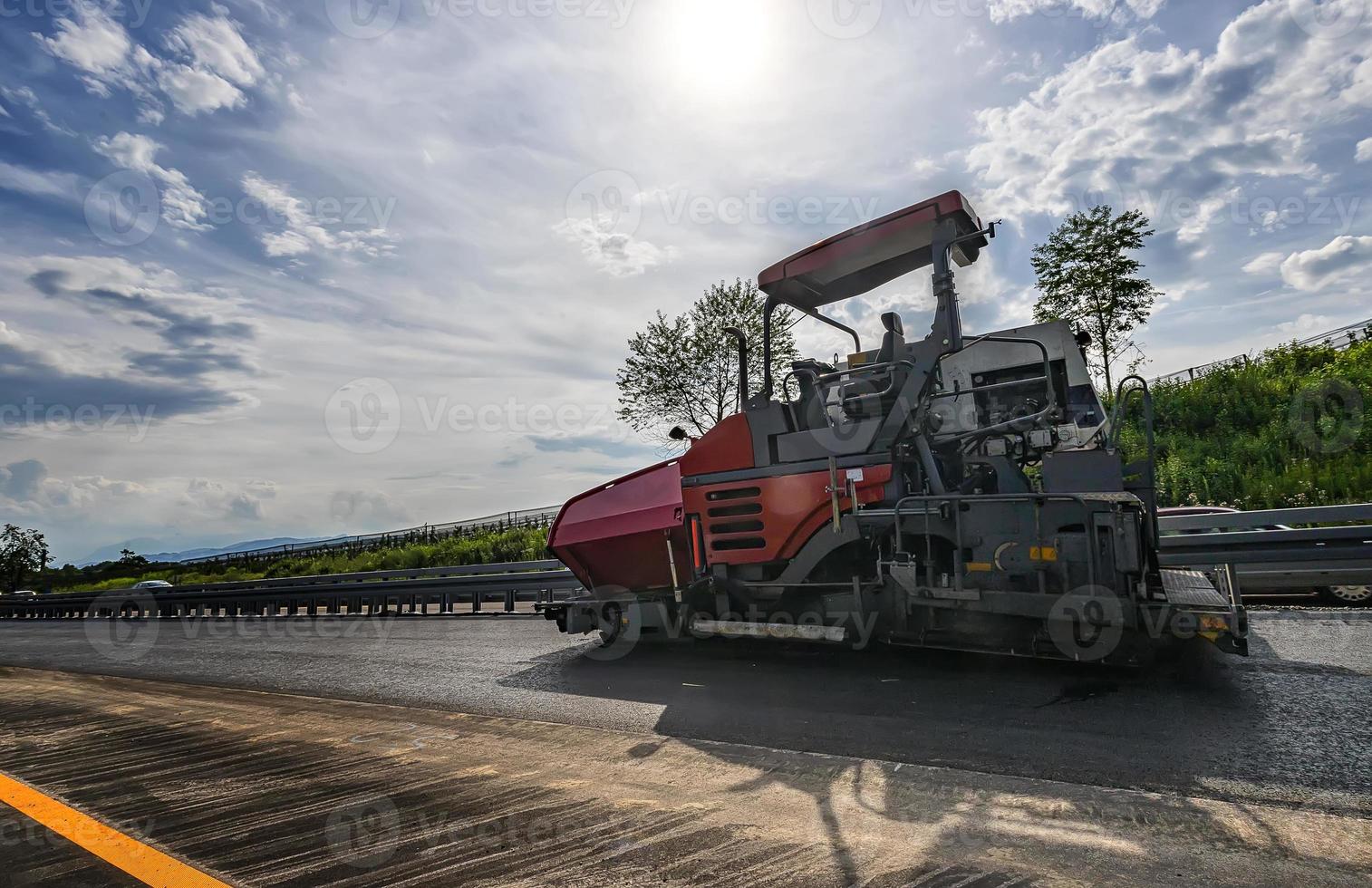 asfalt machine maakt een nieuw weg. een bestratingsafwerkmachine afmaker, asfalt afwerker of bestrating machine plaatsen een laag van asfalt. herbestraten. foto