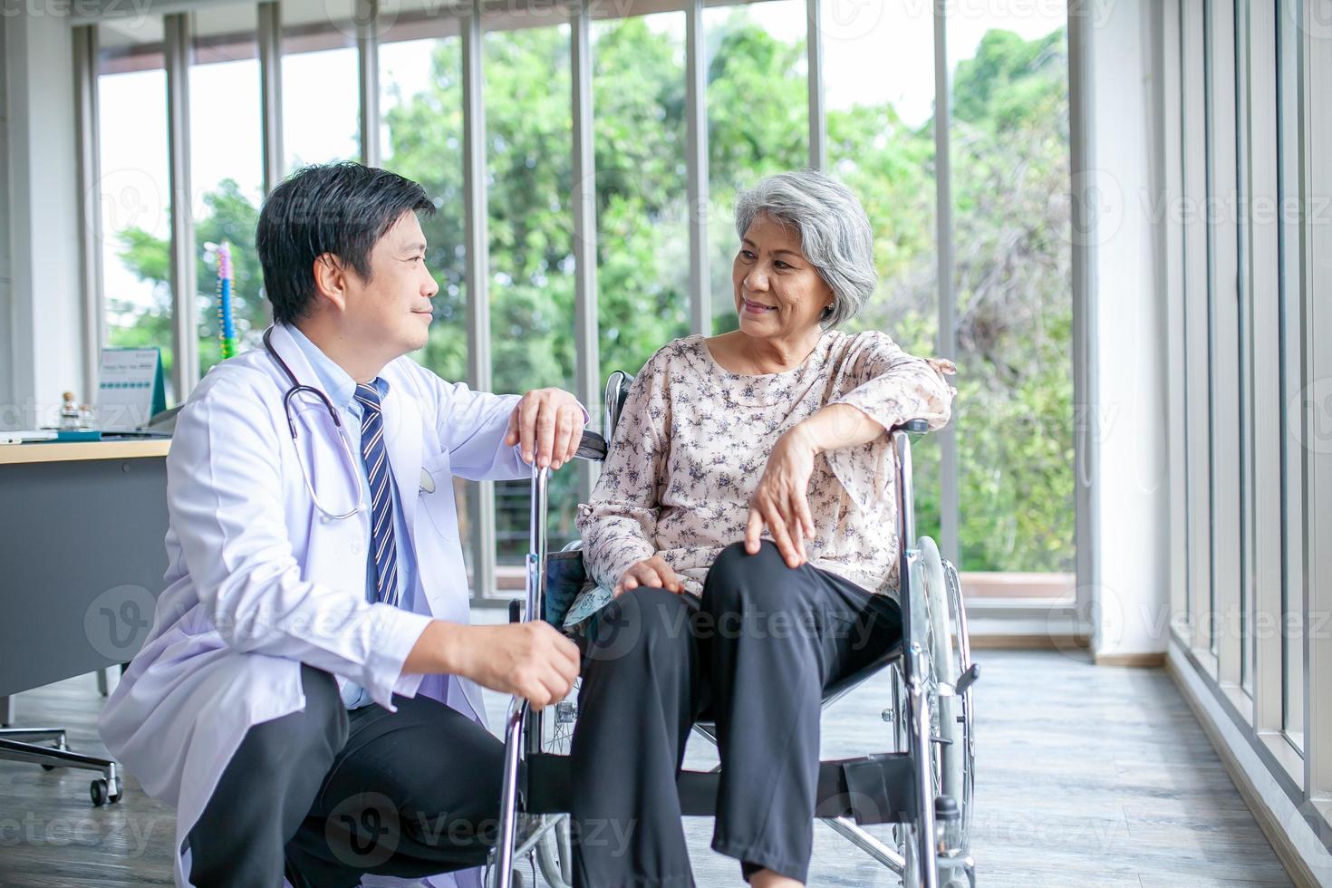 Aziatisch dokter ondersteunen en juichen omhoog senior geduldig in rolstoel praten, glimlachen in comfort Bij huis. gezondheidszorg en geneeskunde concept. foto