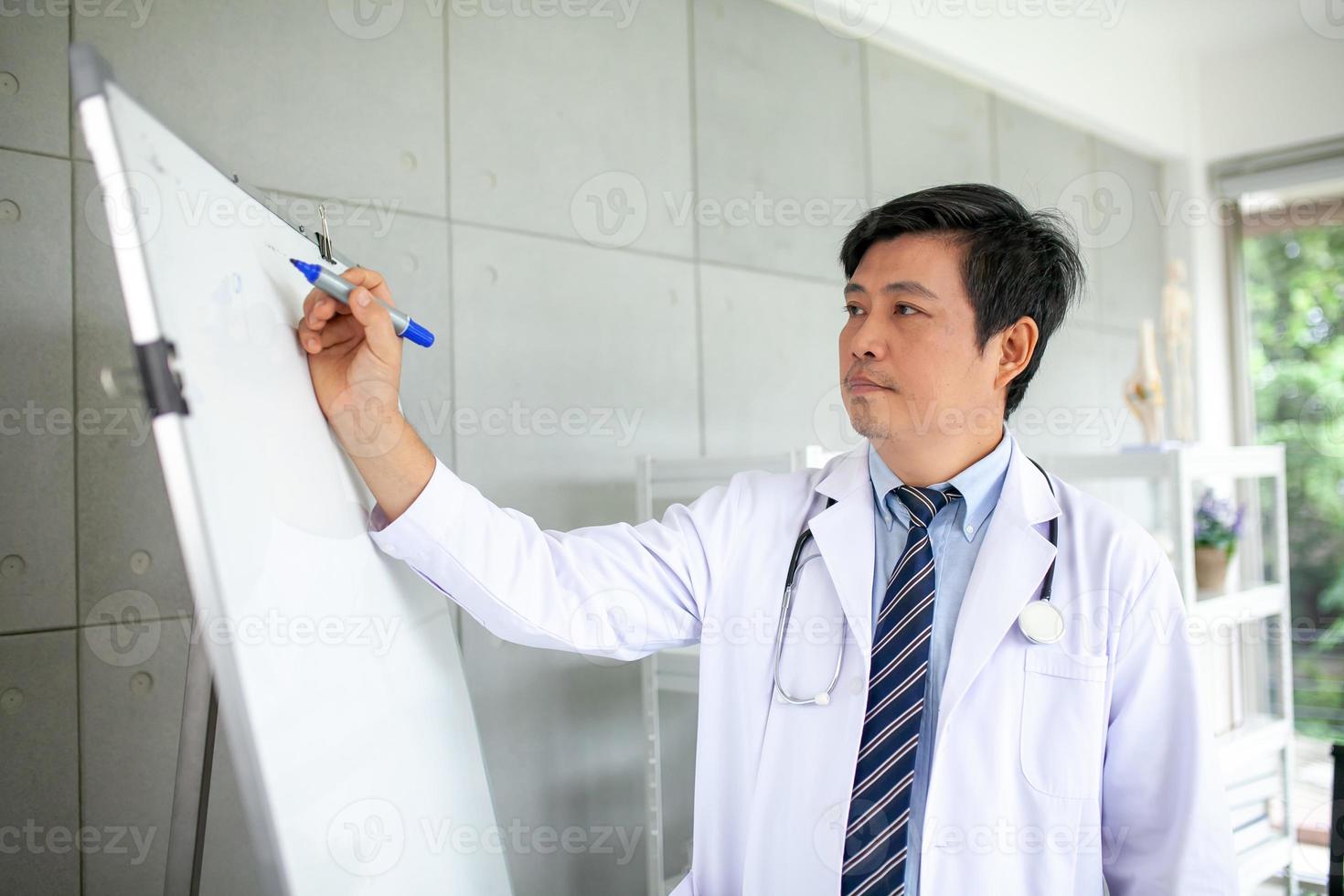 Aziatisch dokter met stethoscoop schrijven Aan bord, gezondheidszorg en geneeskunde concept. foto