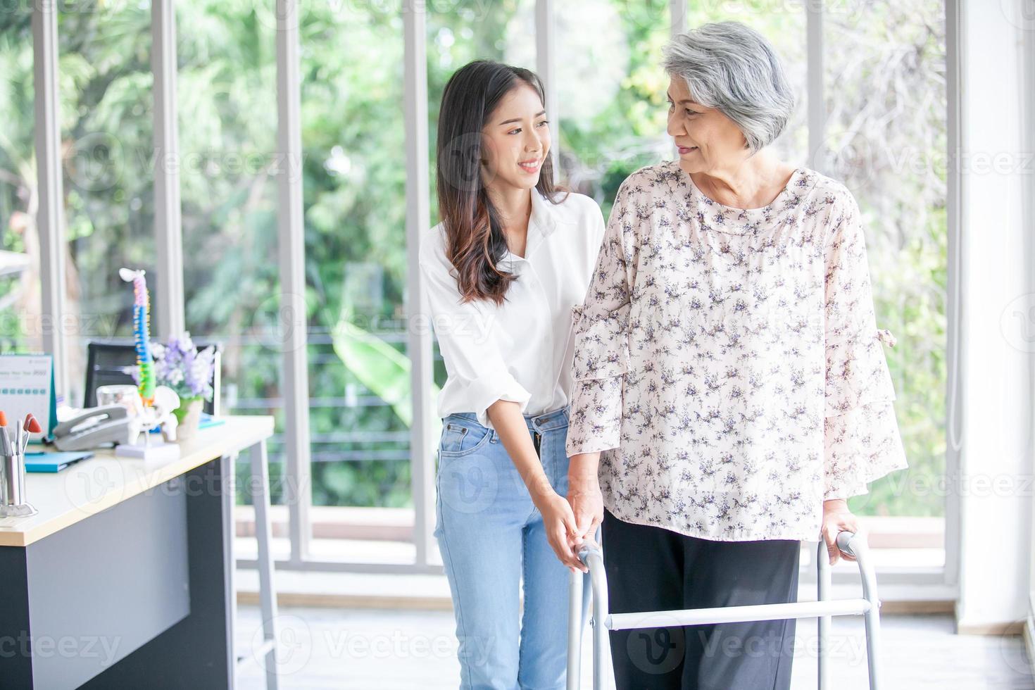 Aziatisch meisje assisteren ouderen vrouw proberen naar wandelen Bij huis, Gezondheid zorg, senior behandeling geduldig Bij huis concept. foto