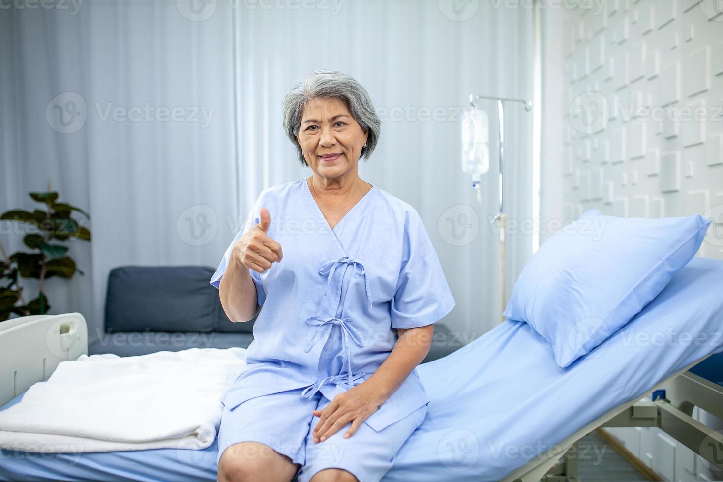 een ouderen vrouw duimen omhoog en glimlachen in de herstel kamer. gezondheidszorg en geneeskunde concept. foto