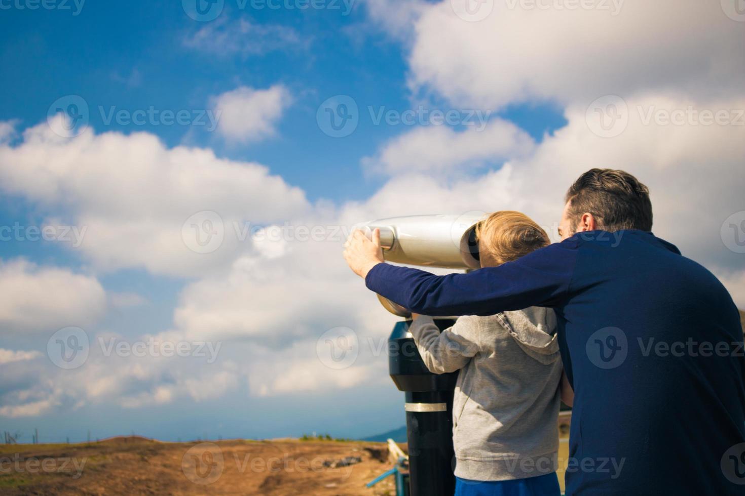 vader en zoon verkennen de lucht door munt bediend verrekijker. foto