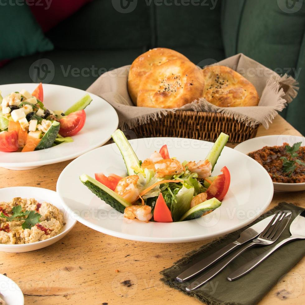 een eettafel vol heerlijke salade op een wit bord naast een broodmand foto