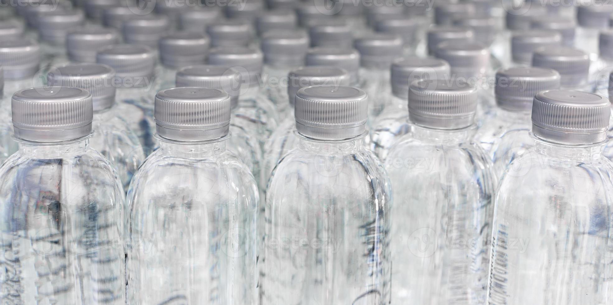 een groot aantal van plastic gebotteld water producten in een drinken water fabriek dat zijn geregeld in een rij aan het wachten naar worden verkocht naar supermarkten. drank en drinken water bedrijf. foto