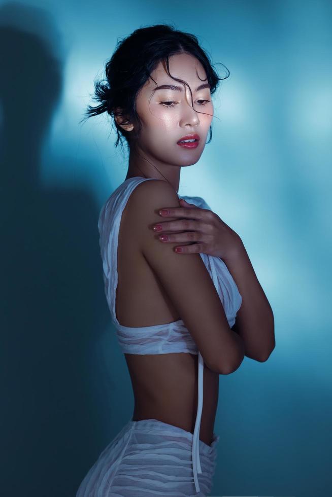 aantrekkelijk jong nat haar- Aziatisch vrouw model- met perfect vers huid Aan onderwater- simulatie van verlichting gezicht zorg gelaats behandeling schoonheidsspecialiste plastic chirurgie lief meisje portret in studio foto
