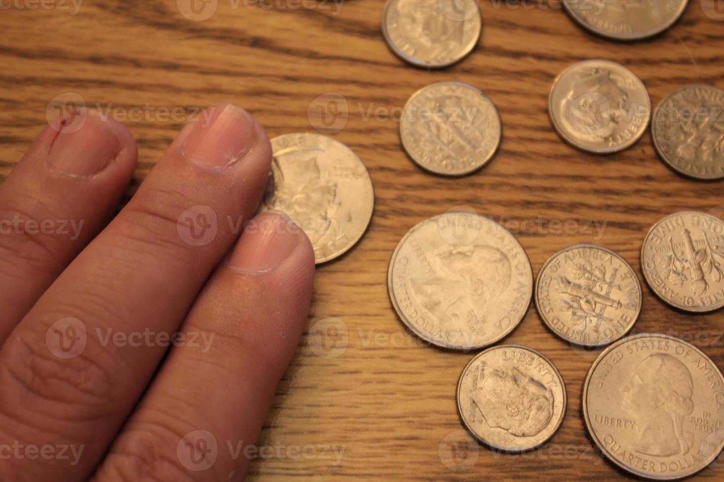 hand- plukken omhoog een kwartaal munt in Amerikaans valuta verspreiding Aan de houten verdieping foto