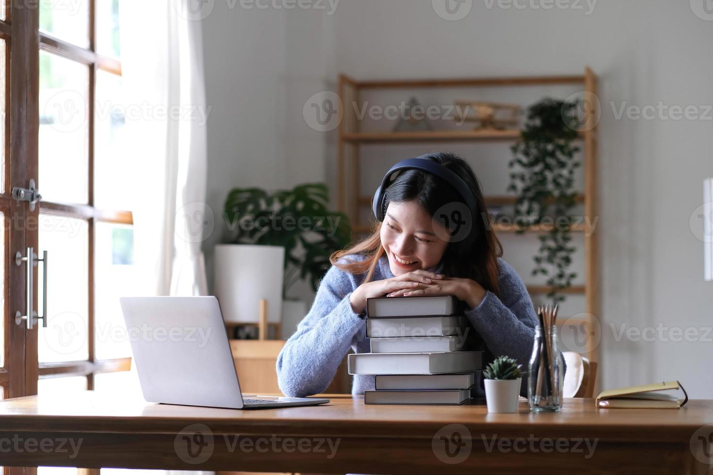 glimlachen Aziatisch vrouw gebruik makend van koptelefoon op zoek Bij laptop scherm luister en leren online cursussen met een video telefoontje met hoofdtelefoons voor online aan het leren foto