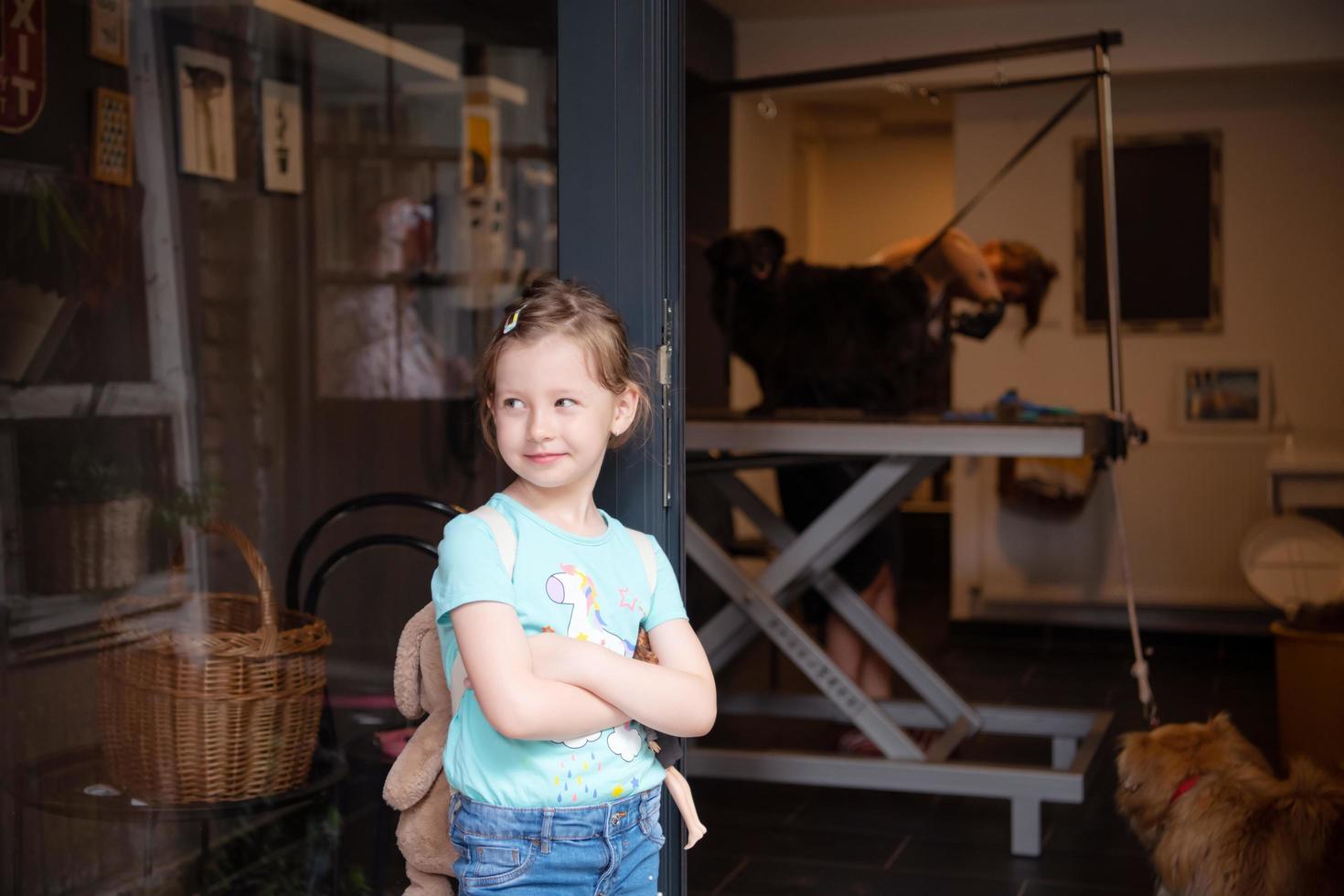 weinig schattig meisje staand in voorkant van schoonheid salon voor dieren foto