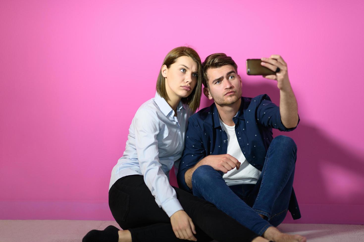 een gelukkig jong paar zittend Aan de verdieping in de huis en maken selfie foto