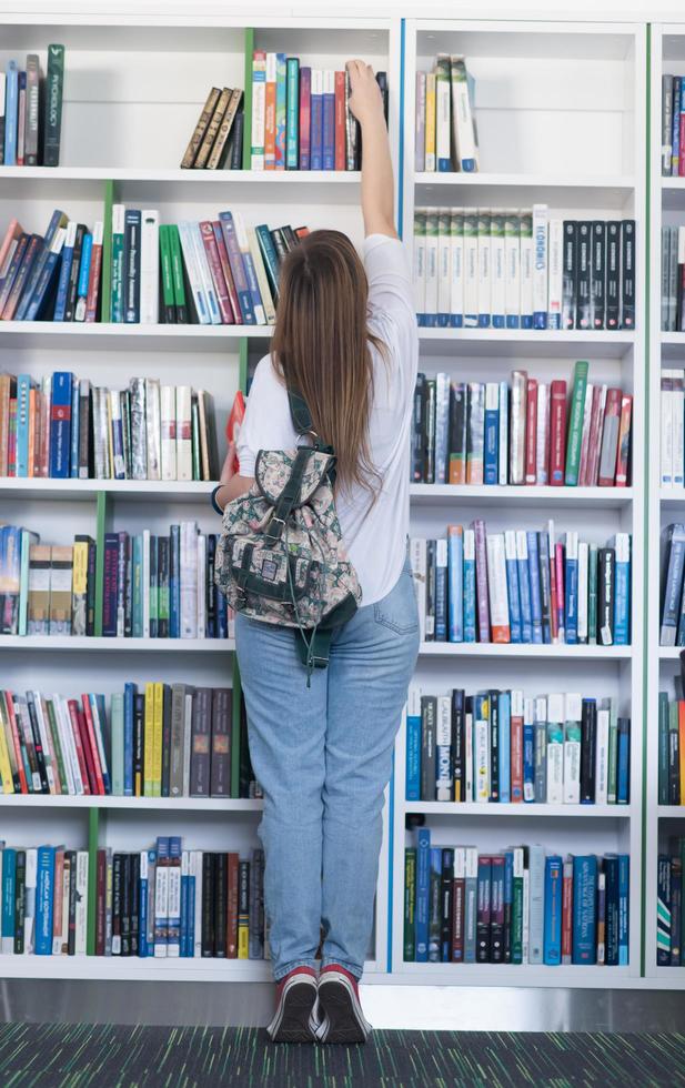 famale leerling selecteren boek naar lezen in bibliotheek foto