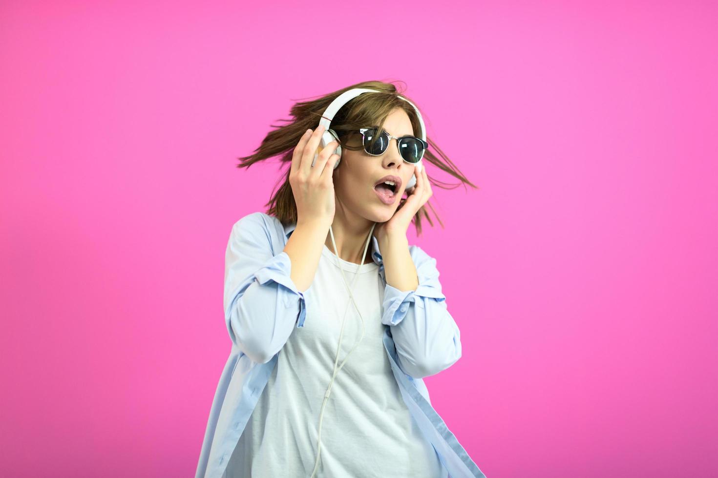 brunette dame in zwart bril dansen en luisteren muziek- isoleren Aan roze achtergrond foto