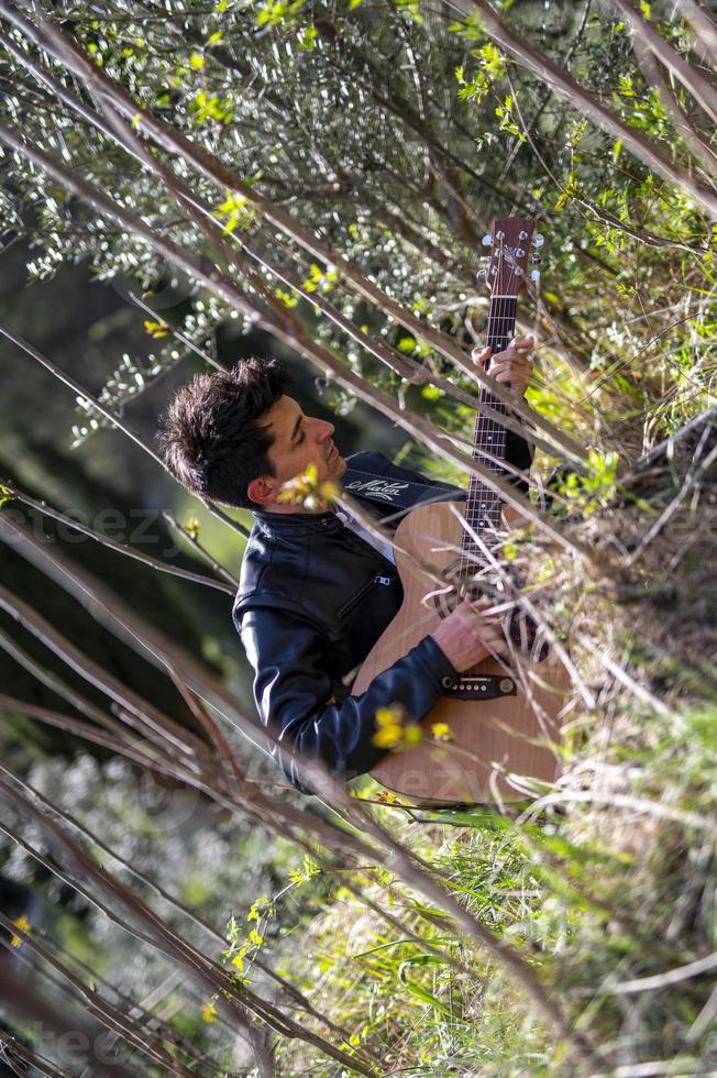 jongen speelt gitaar midden in de natuur foto