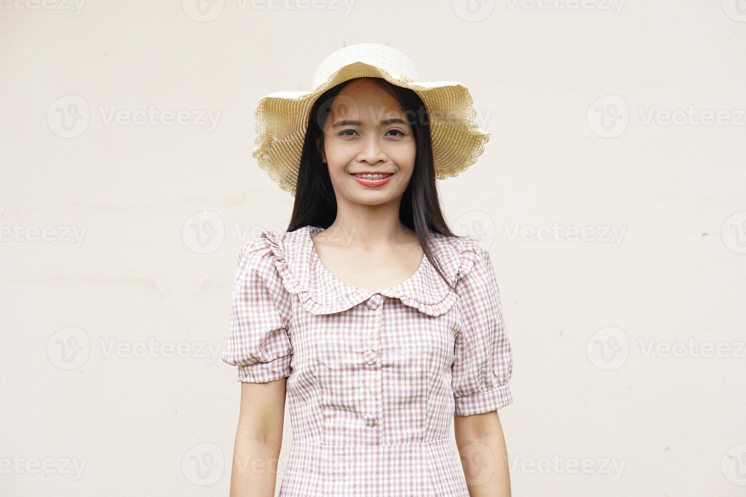 Aziatische vrouw die een hoed draagt die gelukkig glimlacht foto