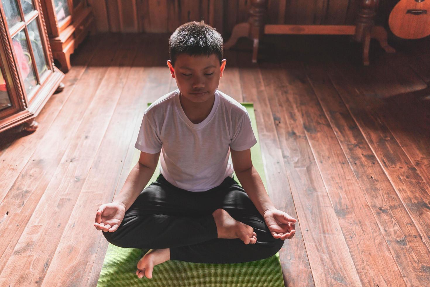 Aziatische jongen mediteert vreedzaam alleen thuis foto