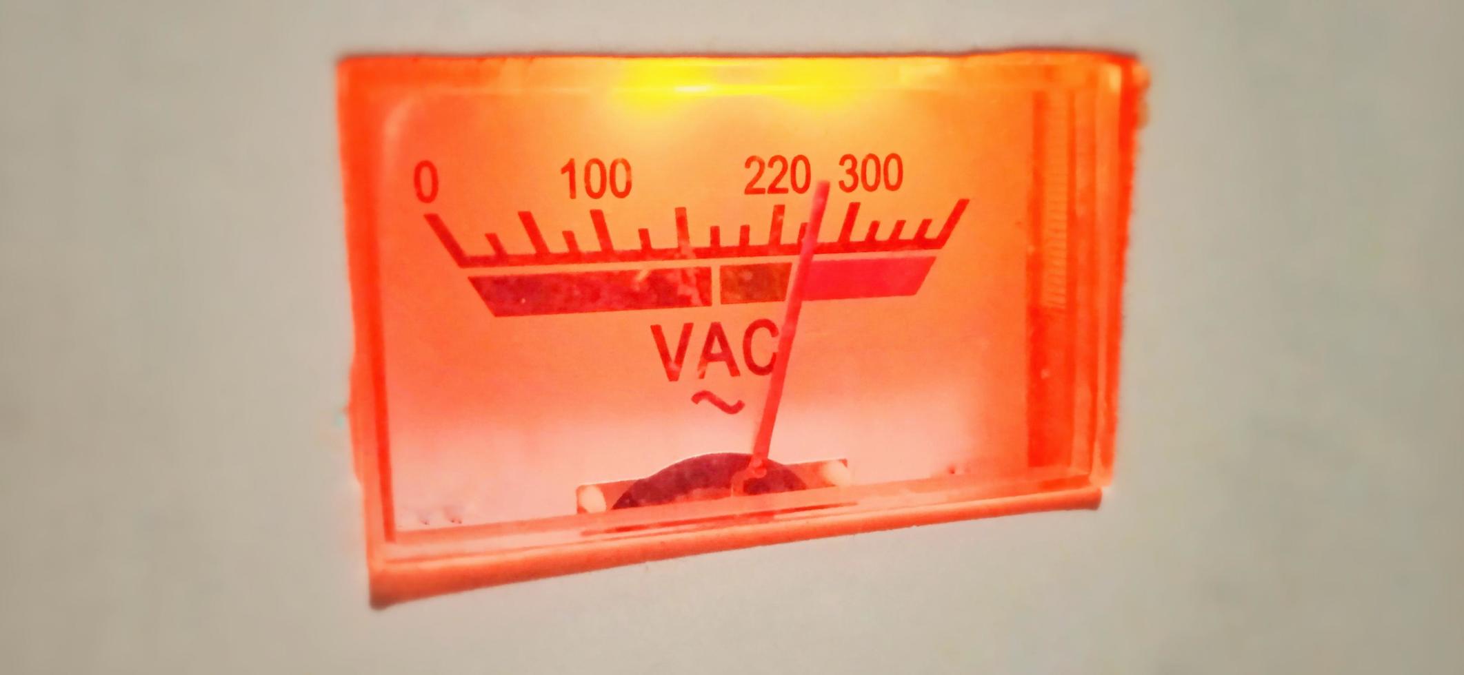 een geïsoleerde rood-oranje oude volt ampèremeter elektrische apparatuur display onder slechte staat. foto
