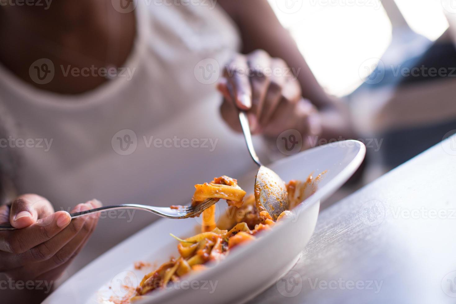 een jonge Afro-Amerikaanse vrouw die pasta eet foto