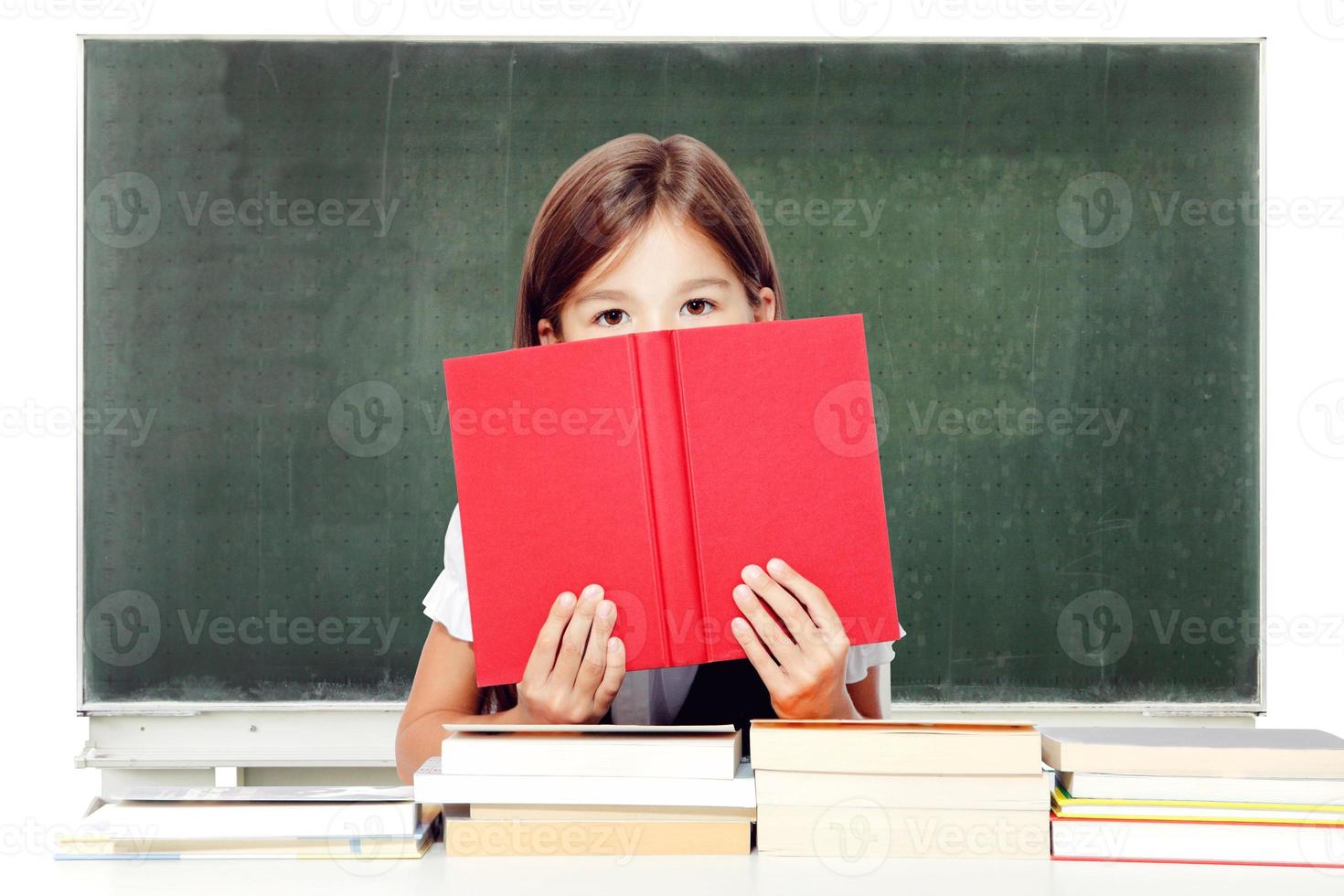 jong schattig meisje zittend Bij de tafel en lezing een boek foto