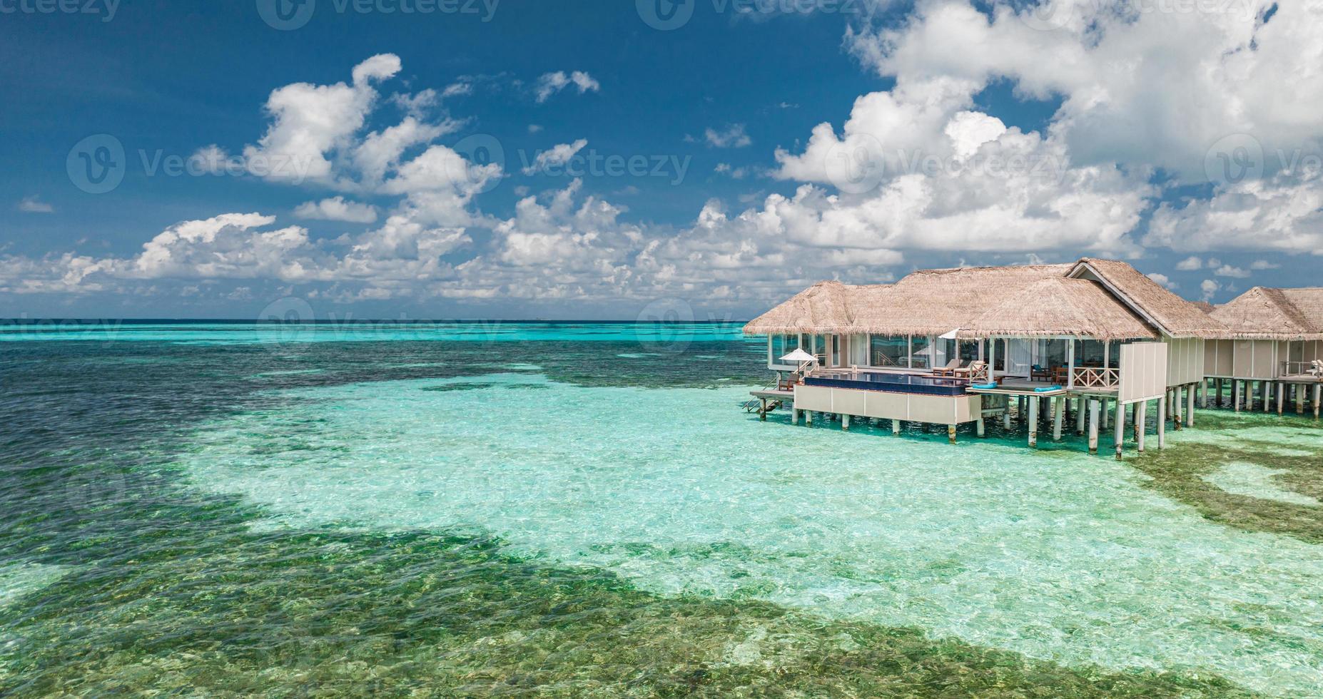 luchtfoto van het eiland maldiven, luxe watervilla's resort en houten pier. mooie hemel en oceaan lagune strand achtergrond. zomervakantie vakantie en reizen concept. paradijs lucht landschap pano foto
