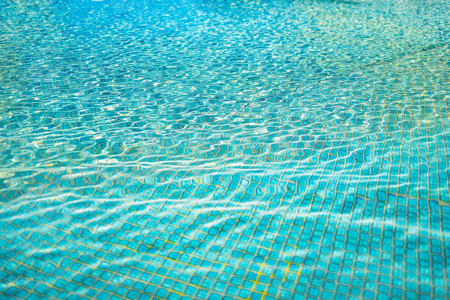 ontspannende oppervlakte van blauw zwemmen zwembad, achtergrond van water. rimpelingen, klein golven van water in zwemmen zwembad met zonnig helder licht. schijnend blauw water rimpeling achtergrond foto