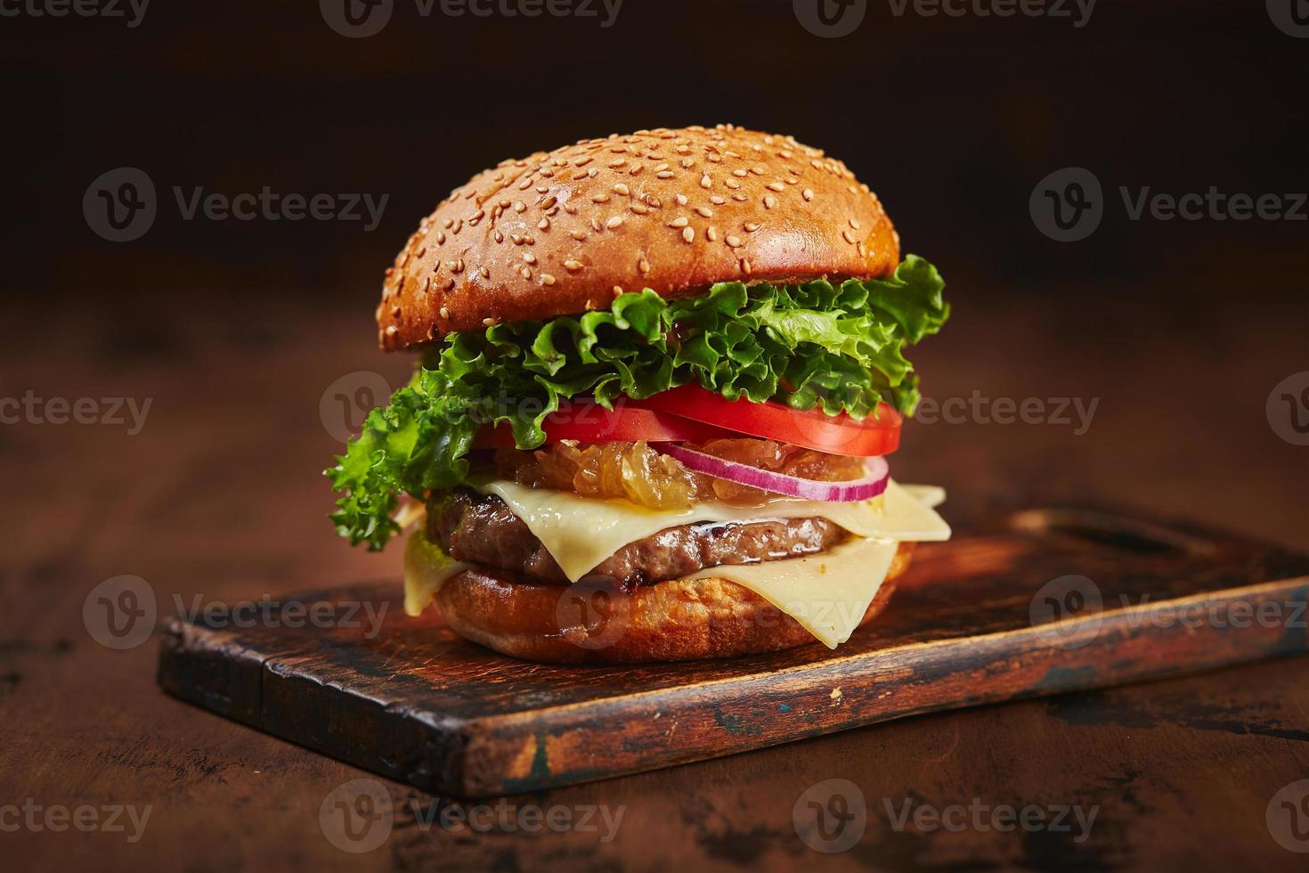 eigengemaakt hamburger met rundvlees, kaas en ui marmelade Aan een houten bord. snel voedsel concept, Amerikaans voedsel foto