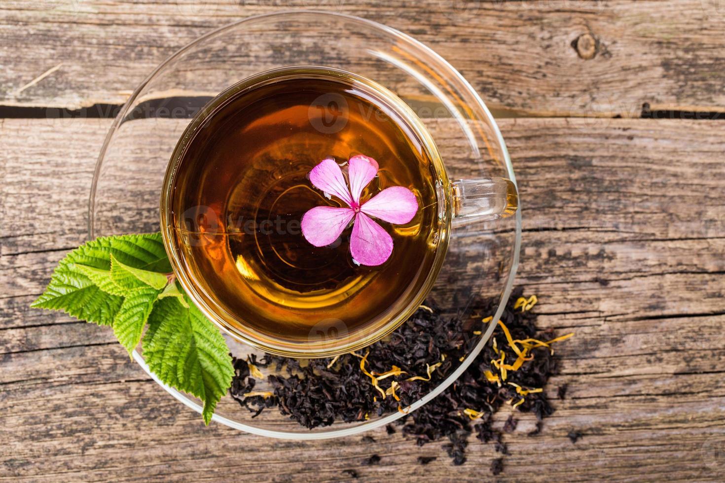 thee met roze bloem en muntblad, op hout foto