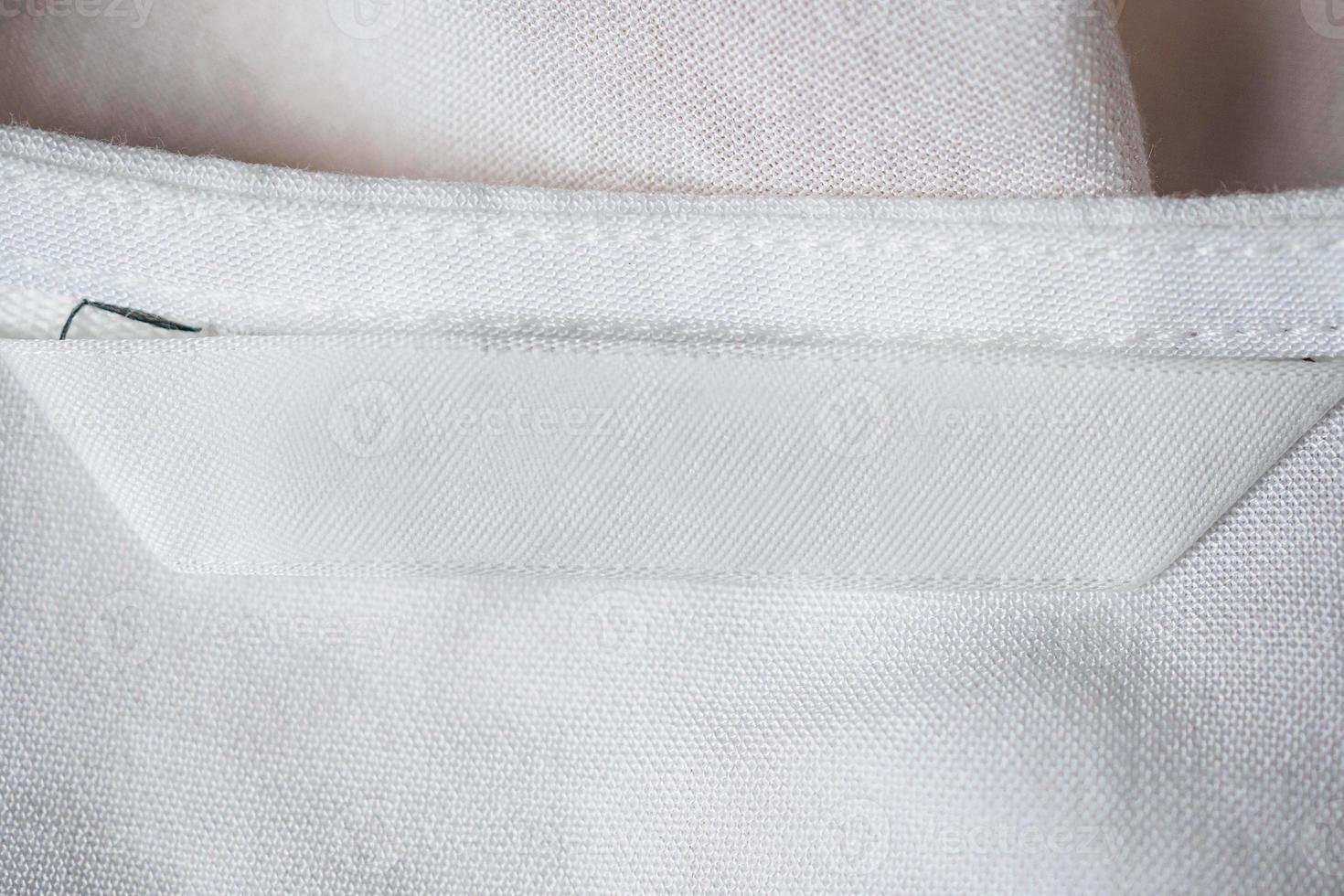 wit blanco wasverzorgingskledinglabel op katoenen overhemd foto