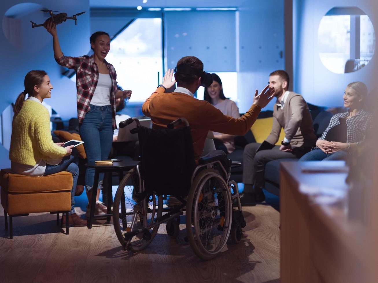 gehandicapt zakenman in een rolstoel Bij werk in modern Open ruimte coworking kantoor met team gebruik makend van virtueel realiteit googles dar bijstand simulatie foto