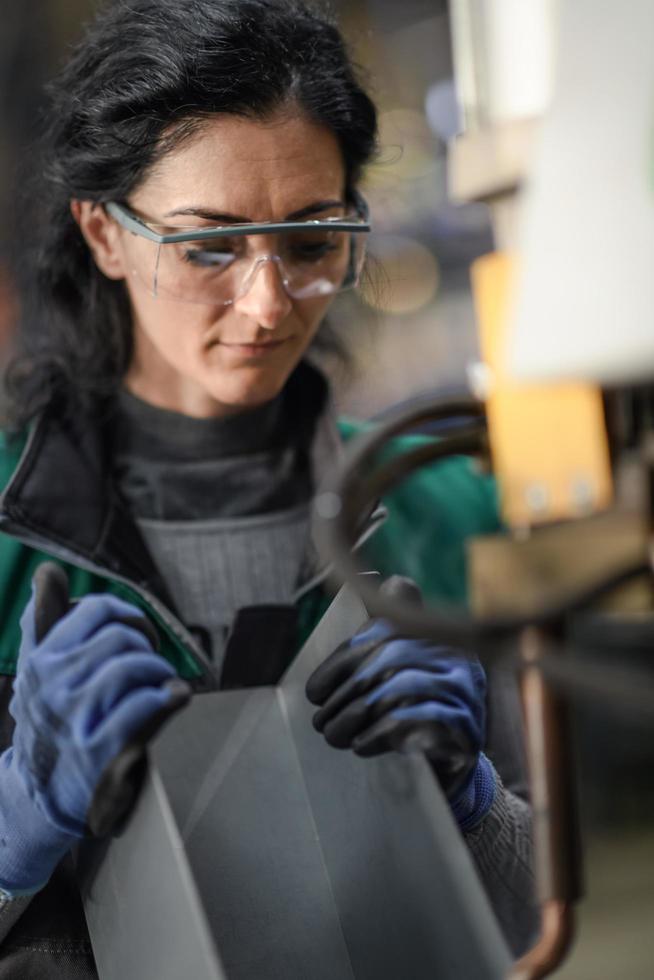 vrouw arbeider vervelend veiligheid stofbril controle draaibank machine naar boren componenten. metaal draaibank industrieel fabricage fabriek foto