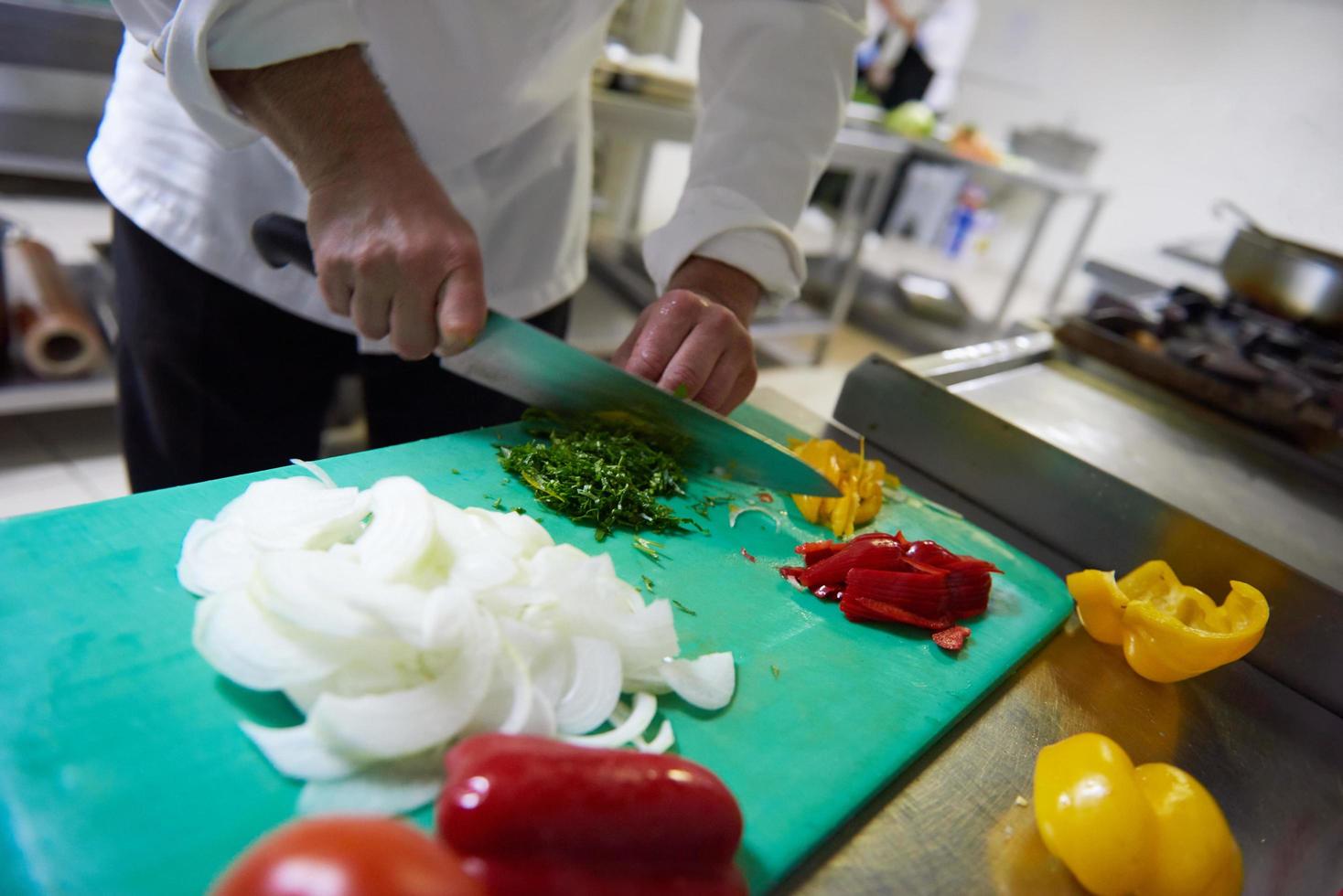 chef in hotel keuken plak groenten met mes foto