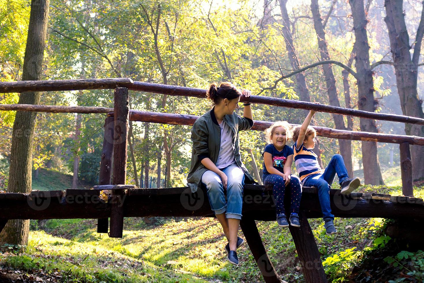 gelukkig familie genieten van een dag in natuur en ontspannende Aan een houten brug. foto