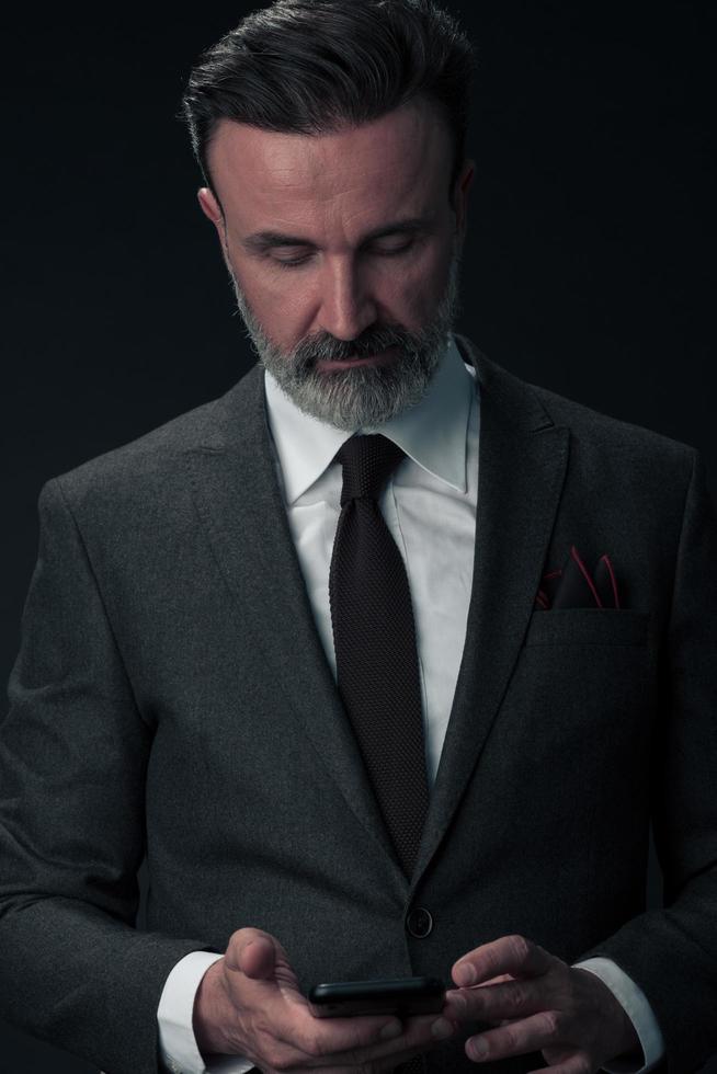 portret van een elegant elegant senior zakenman met een baard en gewoontjes bedrijf kleren in foto studio geïsoleerd Aan donker achtergrond gebaren met handen
