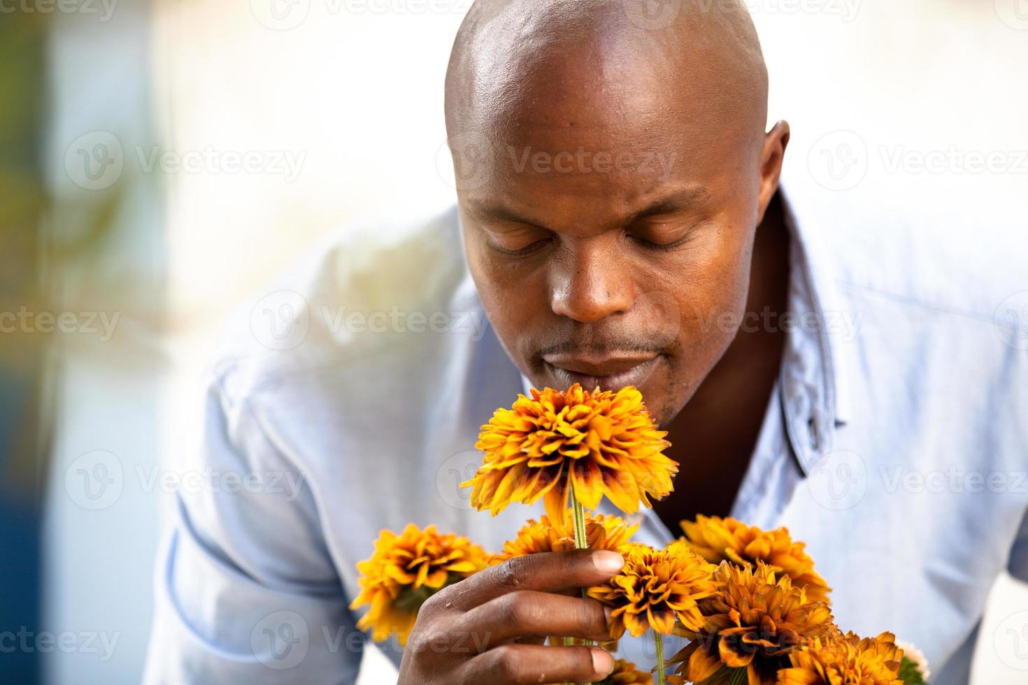Afrikaanse man ruikende bloemen in een bloementuin foto