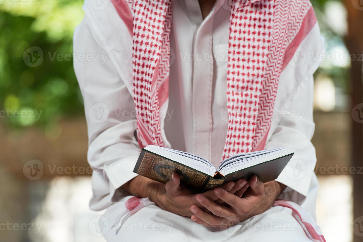 moslim man in dishdasha leest de koran foto