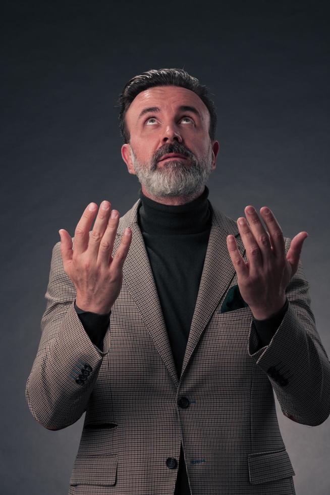 portret van een elegant elegant senior zakenman met een baard en gewoontjes bedrijf kleren in foto studio geïsoleerd Aan donker achtergrond gebaren met handen