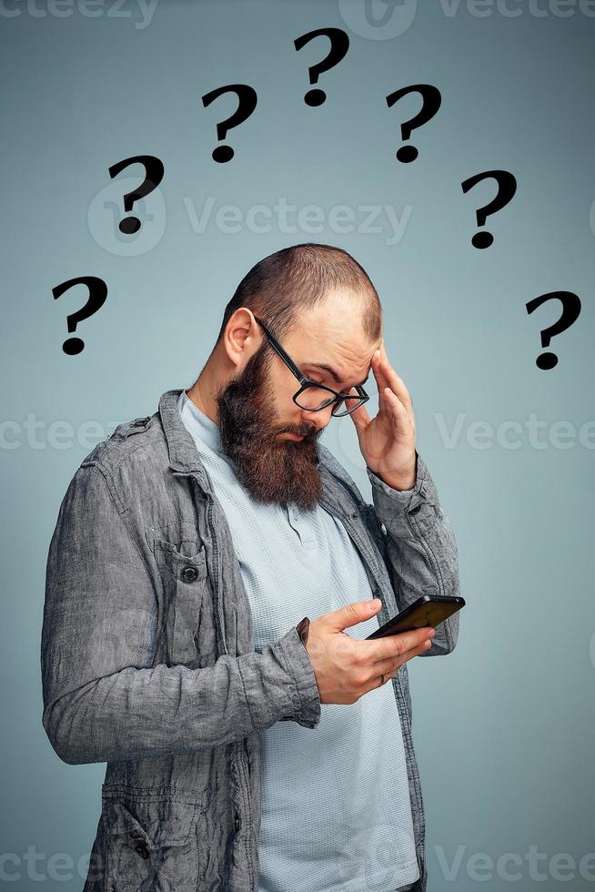 attent Mens met een baard met een telefoon in zijn hand, de oplossing naar het leven problemen. foto