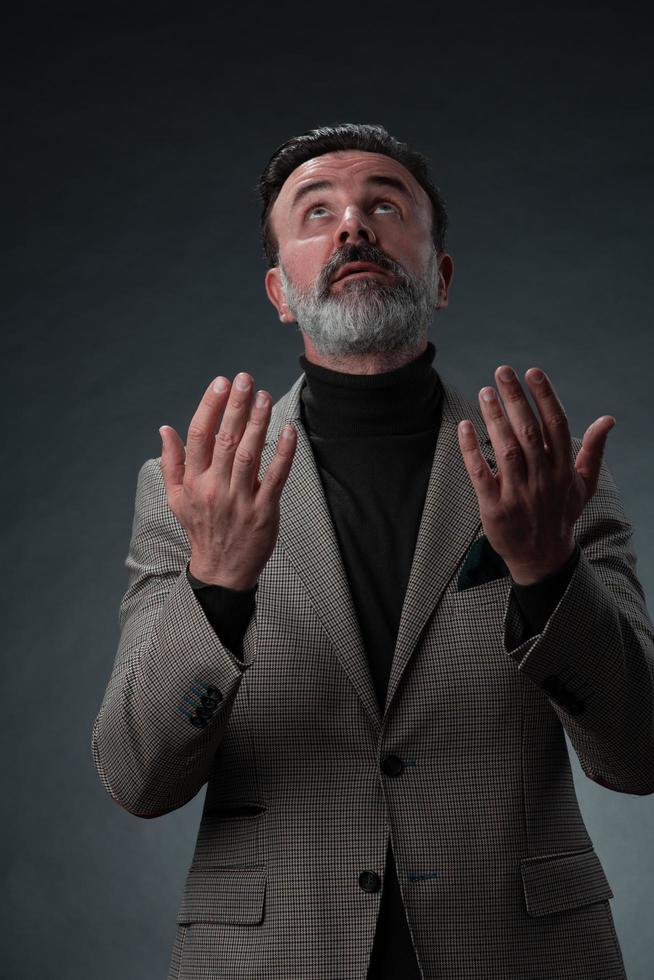 portret van een elegant elegant senior zakenman met een baard en gewoontjes bedrijf kleren in foto studio geïsoleerd Aan donker achtergrond gebaren met handen