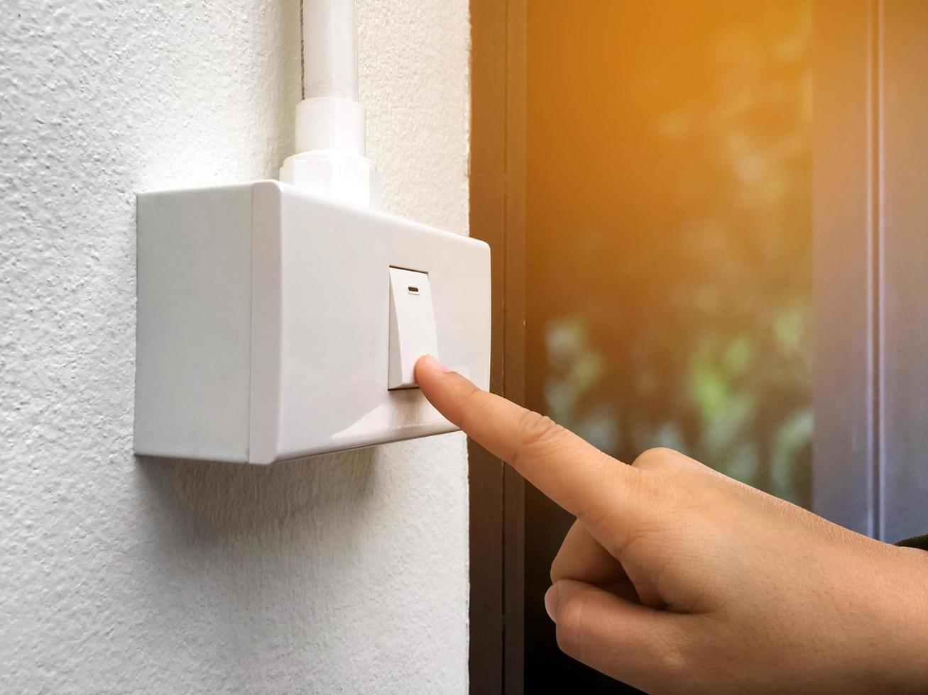 menselijk vinger Aan de schakelaar Aan en schakelaar uit paneel, concept voor beurt uit de elektrisch lamp na gebruik makend van het , voordat gaan uit en naar opslaan onze planeet en globaal opwarming, zacht en selectief focus. foto