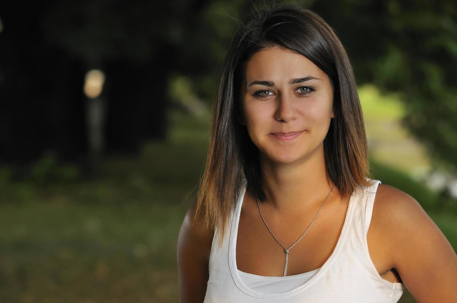 brunette schattig jong vrouw glimlachen buitenshuis in natuur foto