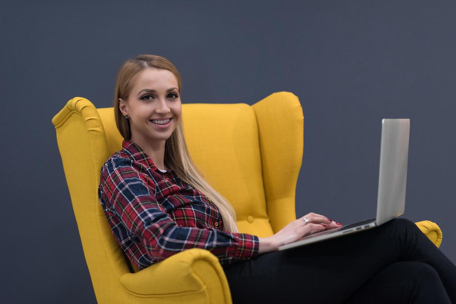 opstarten bedrijf, vrouw werken Aan laptop en zittend Aan geel fauteuil foto