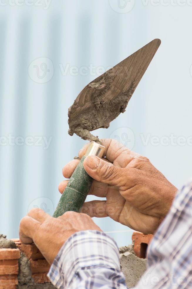 metselaar werken in bouw plaats van een steen muur foto