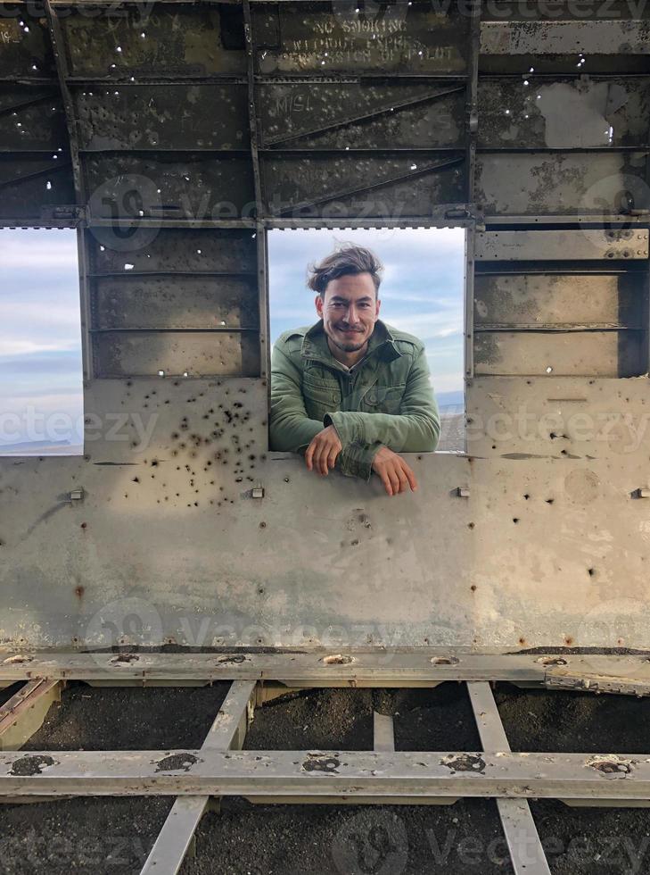 Mens met langer haar- op zoek door de venster van een vlak wrak foto